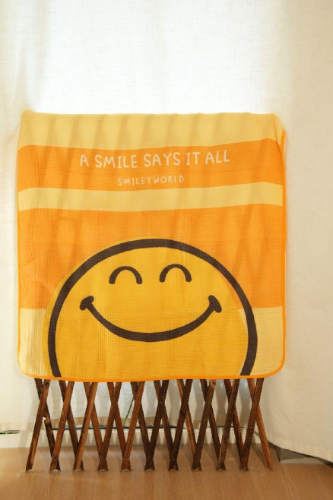 Orange towel with smiley face and text on a wooden stand